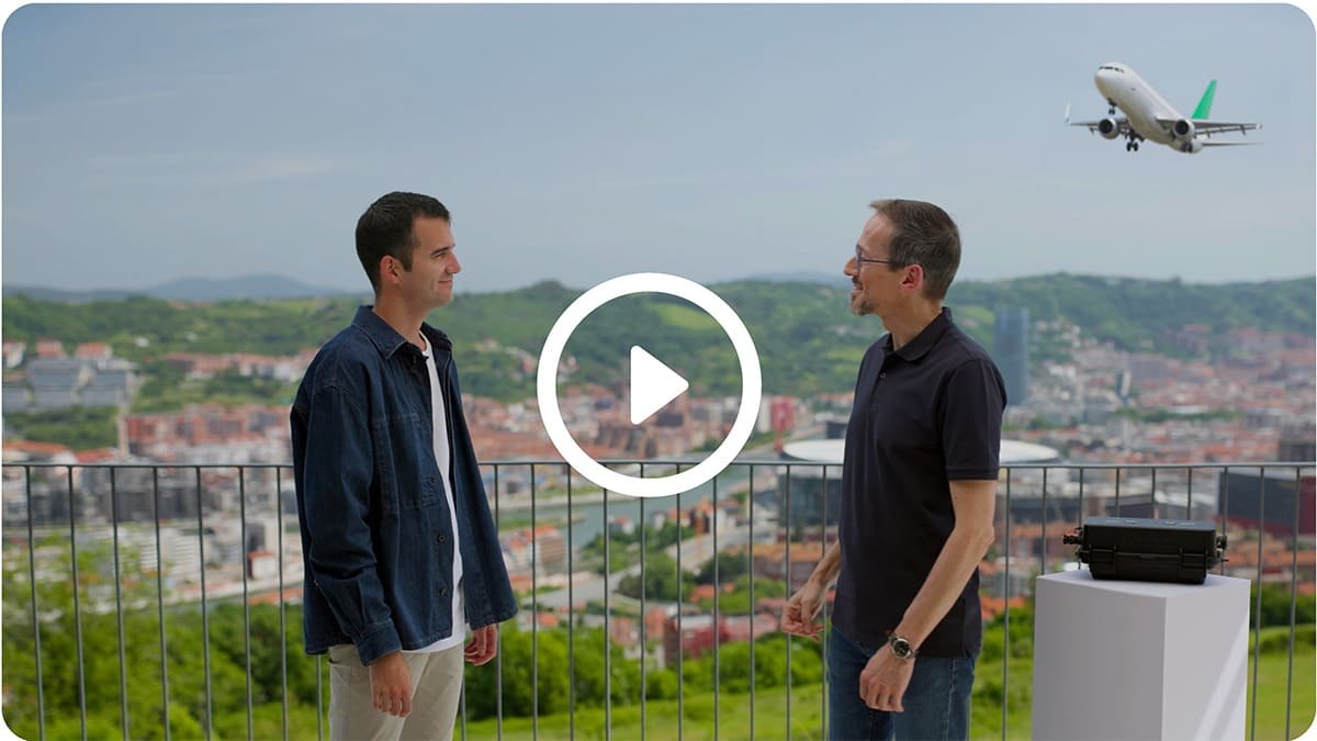 Dois engenheiros da Suntrack conversando em um terraço com vista para Bilbao, ao lado de uma maleta de transporte sobre um pedestal