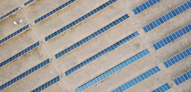 Vista aérea de várias fileiras de rastreadores solares sobre terreno árido