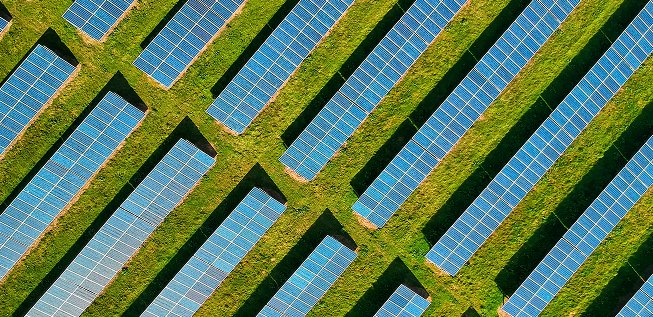 Vista aérea de várias fileiras de rastreadores solares sobre um campo verde